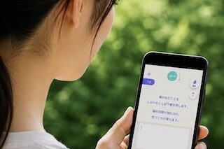 Woman seen from behind holding a smartphone with a messaging app open, typing outdoors in a park.